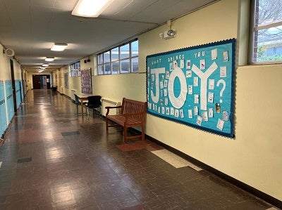 bulletin board in hallway with the word joy prominently displayed